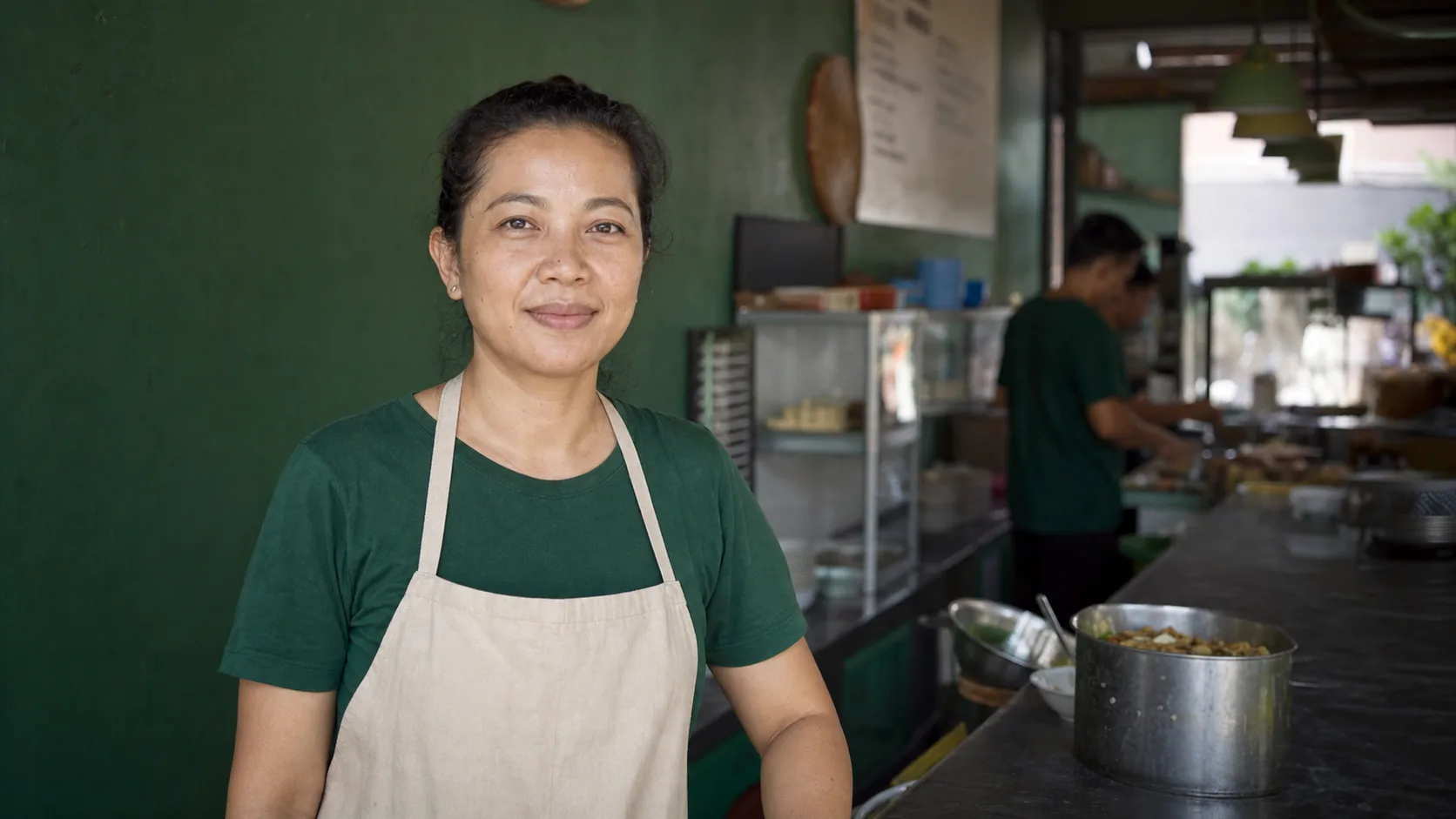 Rina, a food business owner, standing in front of her shop